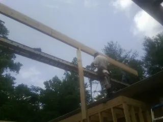 Carpenter setting a ridge beam over a new addition frame — Ice Dam Removal by Roofing Brothers in Hannaford