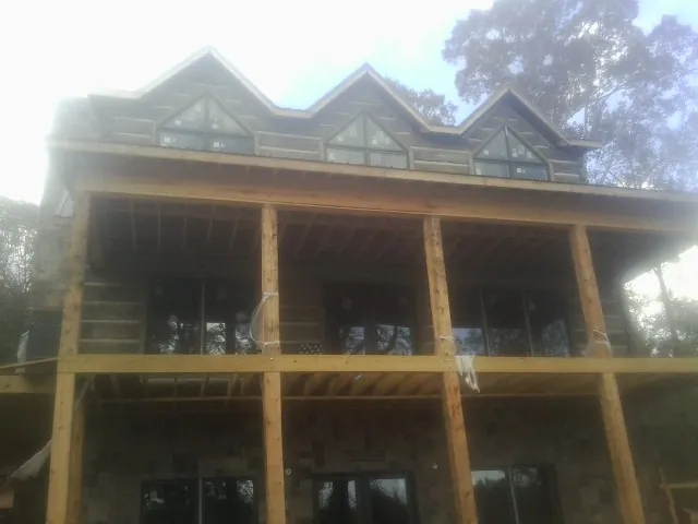 Dormers and porch framing on a large log home under construction — Roof Coating work by our crew in Hannaford