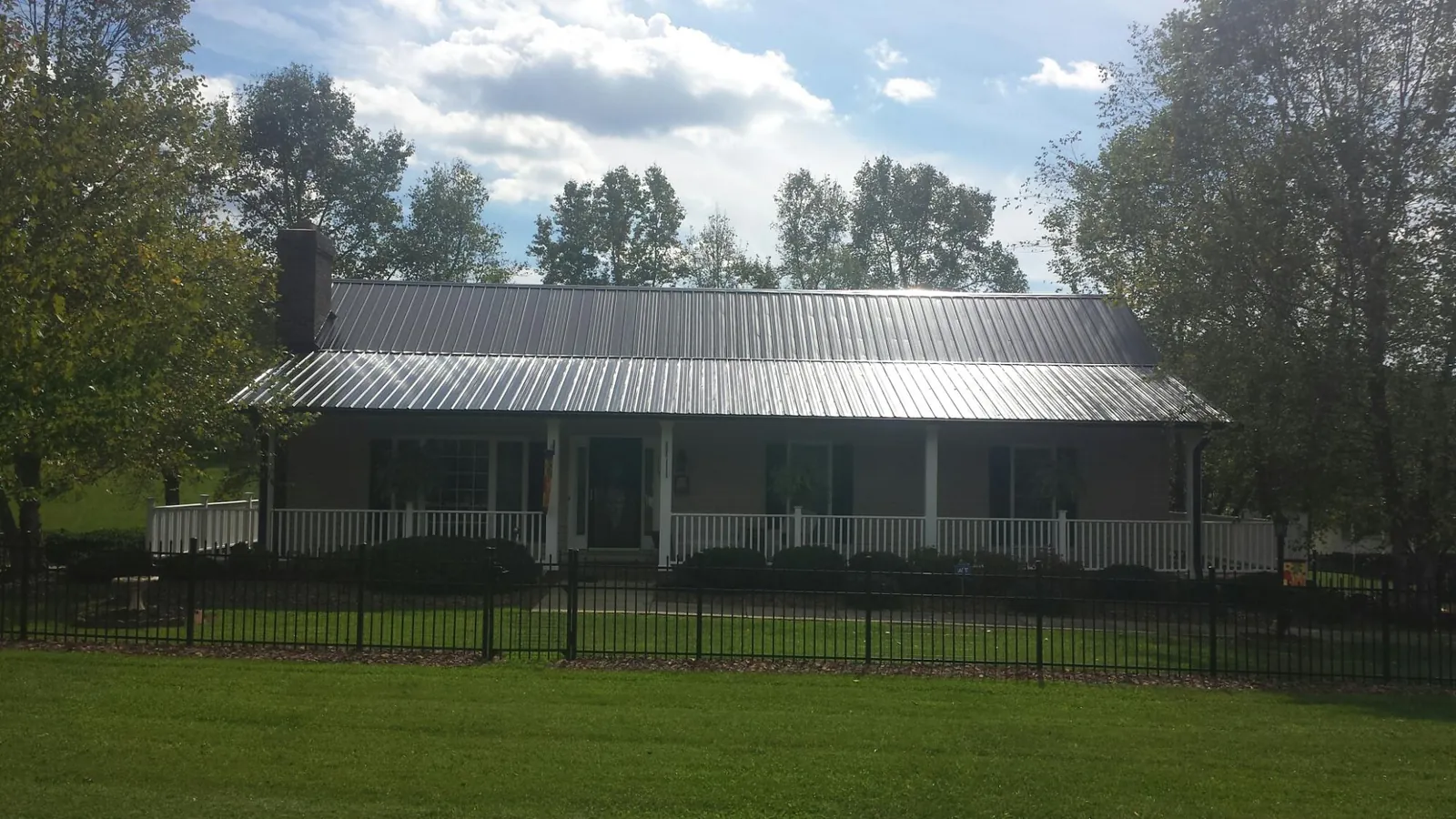 Gray metal roof on a brick ranch with a full width front porch — Gutter Guard Installation work by our crew in Hannaford