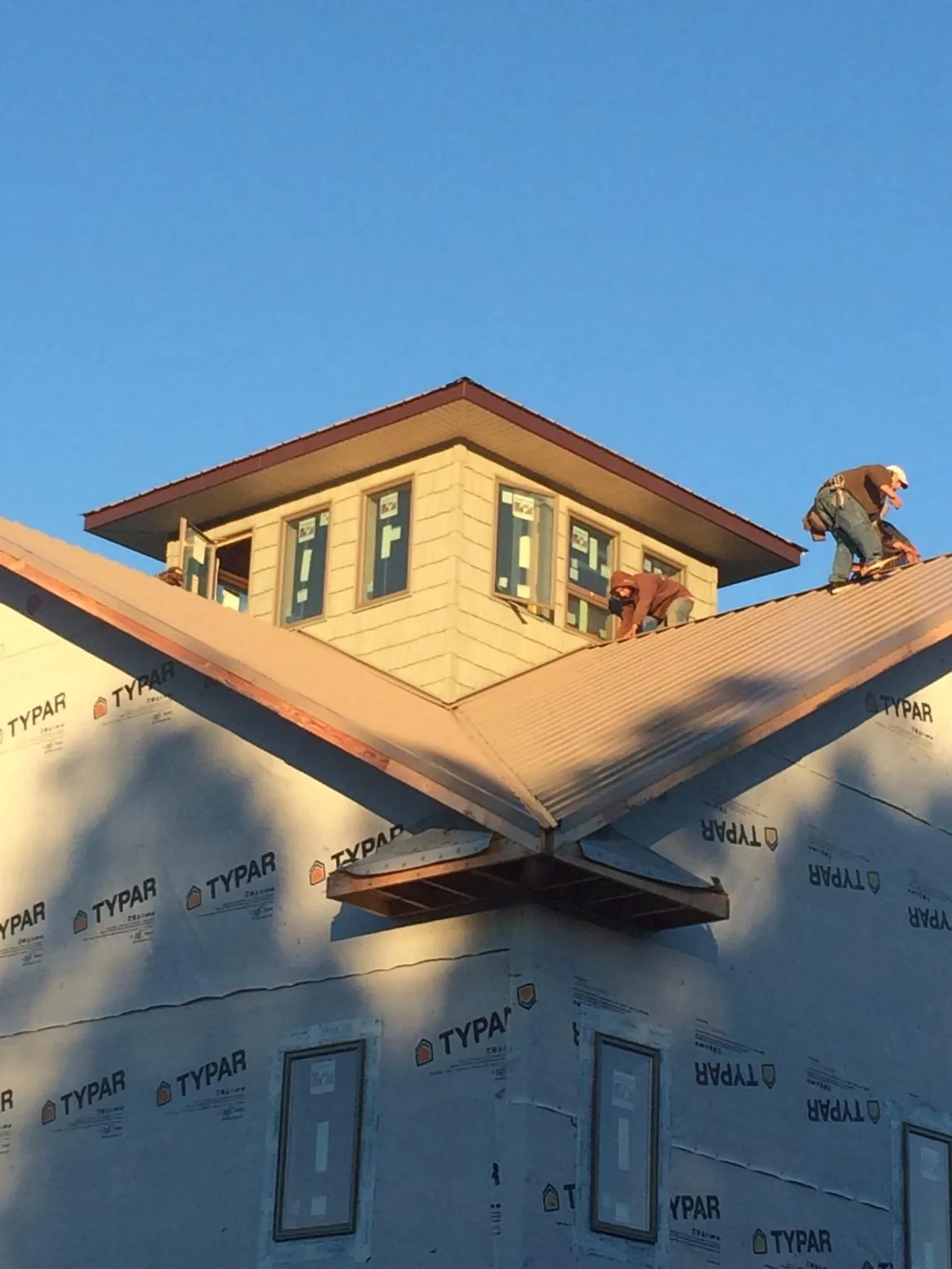 Roofers working around a rooftop cupola on a new metal roof at sunset — Roof Waterproofing in Hannaford by Roofing Brothers
